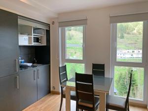 a dining room with a table and chairs and two windows at Apartamentos Vallnord 3000 in Arinsal