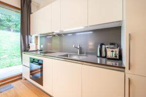 eine Küche mit weißen Schränken und einer Spüle in der Unterkunft Residenz Cuolm Liung 52 in Laax