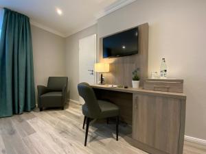 een kamer met een bureau, een televisie en 2 stoelen bij Mertinkus Nordseehotel in Cuxhaven
