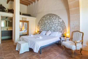 a bedroom with a large white bed and a chair at Finca Agroturismo Es Pujol in Santanyi