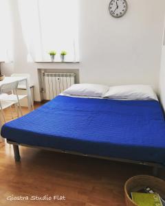 niebieskie łóżko w pokoju z zegarem na ścianie w obiekcie Giostra Studio Flat w Trieście