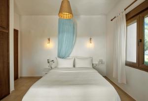 a bedroom with a large white bed with a blue curtain at Sanidiamonds in Sani Beach