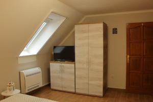 a bedroom with a skylight and a dresser with a television at Hegylánc Fogadó in Sótony