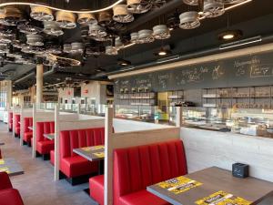 a restaurant with red chairs and a counter with food at RINGRAST das Erlebnishotel beim Red Bull Ring in Spielberg