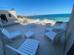 a patio with white chairs and tables and the ocean at Vila Seascape in 2 Mai
