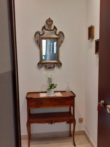 een spiegel aan een muur naast een tafel met een wastafel bij La casa di Sabrina in Verona