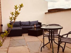 een patio met een bank en een tafel en stoelen bij Fir Tree Barn in Pollington