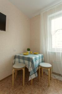 a table with two chairs and a table with yellow dishes on it at СВЕЖО! Basic - Студия У Озера На Бурнаковской in Nizhny Novgorod