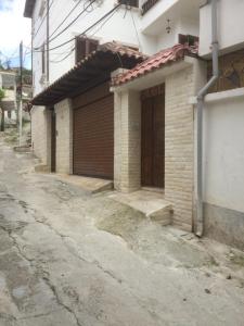 uma casa de tijolos com uma porta de madeira numa rua em Apartment Koka em Berati