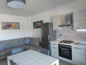 een keuken en een woonkamer met een bank en een tafel bij Shardana in Quartu SantʼElena