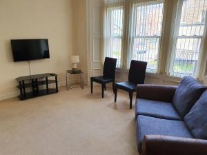 a living room with a couch and two chairs and a tv at Flat 1 Castlebank house Flats in Dingwall