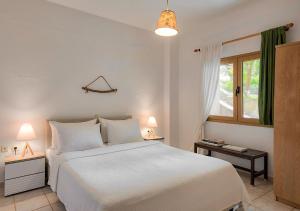 a bedroom with a large white bed and a window at Sanidiamonds in Sani Beach