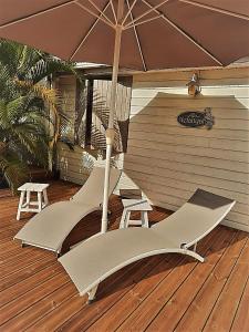 a patio with two chairs and an umbrella at Les Gîtes de Bergette in Petit-Bourg