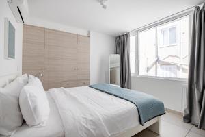 Un dormitorio con una cama blanca con una ventana grande. en Supreme D1 Penthouse 131m² in Syntagma, en Atenas