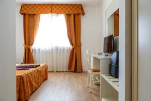 um quarto com uma cama, uma televisão e uma janela em Hotel Villa Sofia em Viterbo