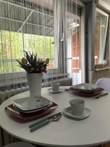 a table with plates and cups and a vase with flowers at Apartman studio Pavle i Petra in Sremski Karlovci