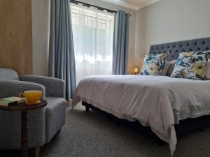 ein Schlafzimmer mit einem Bett, einem Stuhl und einem Fenster in der Unterkunft Linden Gap Guesthouse in Johannesburg