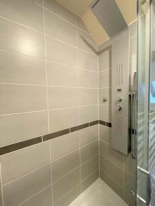 ein Bad mit einer Dusche und weißen Fliesen in der Unterkunft Résidence Investar appartement 5 in Montluçon