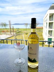 a bottle of wine and a wine glass on a table at Vízpart Honvéd Apartman in Balatonlelle