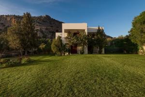 a house with a large lawn in front of a mountain at Emerald Dawn Villa in Pefki Rhodes