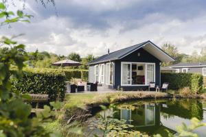 ein schwarzes Cottage mit einem Teich davor in der Unterkunft Salland 4 persons in Rijssen