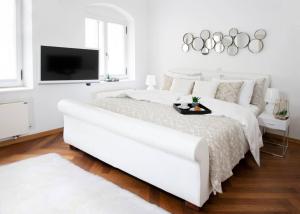 a white bedroom with a large white bed and a flat screen tv at Address Deluxe Downtown in Ljubljana