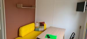 um quarto lego com um sofá amarelo e uma mesa em Mini-chalet - Vakantiepark 't Urkerbos em Urk