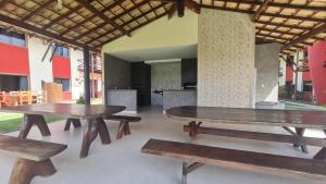a group of picnic tables sitting under a building at Condomínio Conchas e Corais in Barra Grande