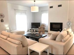 una sala de estar con 2 sofás blancos y una mesa. en Villa Korais Luxury 3br apt with sea view, en Tesalónica