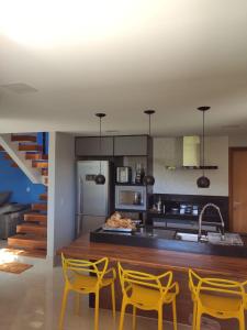 a kitchen with yellow chairs and a kitchen counter at Recanto do Vale in Santa Teresa
