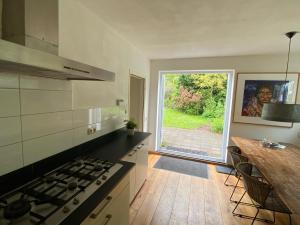 een keuken met een fornuis en een groot raam bij Ecolodge Bergzicht de Bosuil - vakantiehuis aan het bos in Lochem