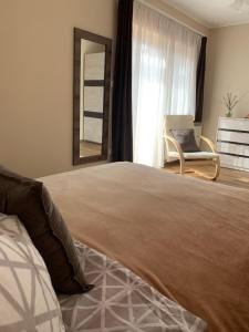 una camera da letto con un letto grande con una sedia e uno specchio di Miseta Apartman a Fonyód