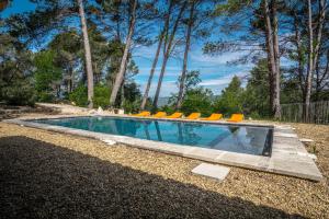 a swimming pool with orange lounge chairs around it at Stunning panoramic views and heated pool in Roussillon in Roussillon