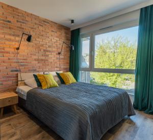 Un dormitorio con una pared de ladrillo y una cama con almohadas amarillas. en Apartamenty Homely Place Centrum en Poznan