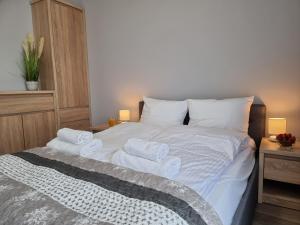 a bedroom with a bed with white sheets and towels at Apartament Rodzinny - 365PAM in Gąski