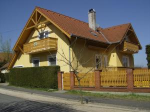 una casa gialla con una recinzione in legno di Miseta Apartman a Fonyód