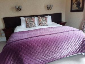 a large bed with a large purple blanket on it at No 45, Ballater in Ballater