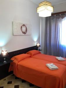 um quarto com uma cama com lençóis laranja e 2 candeeiros em Casa Vacanza I Due Mori em Avola