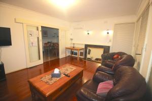 a living room with a leather couch and a coffee table at Garden Guesthouse - Melbourne Airport Accommodation in Melbourne