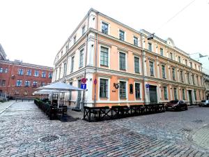 un gran edificio con mesas delante en una calle en Oldtown Palasta Apartments en Riga