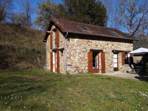 a small stone building with a grassy field in front at Chambre D Hôtes dans maisonnette indépendante in Saint-Sornin-Lavolps