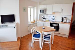 奥斯赛拜-塞林Fewo 20 mit Strandkorb und Balkon的厨房里有一张桌子和几把椅子