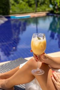 a woman holding a drink in front of a pool at Pousada Ponta da Vigia in Penha