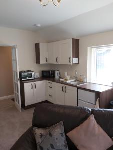 uma cozinha com armários brancos e um sofá num quarto em Oaktree Lodge em Doncaster