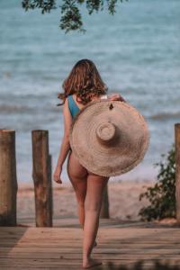 uma mulher a andar numa doca com um chapéu em Pousada Ponta da Vigia em Penha