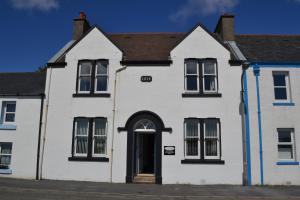 a white house with black windows and a door at Eilidh’s Guest House in Port Ellen