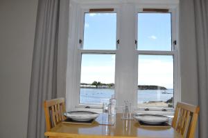a table with chairs and a window with a view of the ocean at Eilidh’s Guest House in Port Ellen