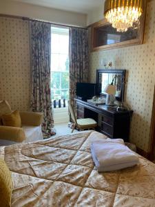 a bedroom with a bed and a desk and a mirror at Plas Hafod Hotel in Mold