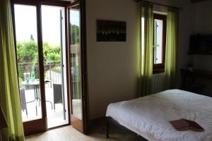 um quarto com uma cama e uma porta para uma varanda em Agriturismo Al-Bor em Lazise