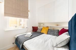 a bedroom with a bed with colorful pillows and a window at Warsaw Premium Apartment President Palace in Warsaw